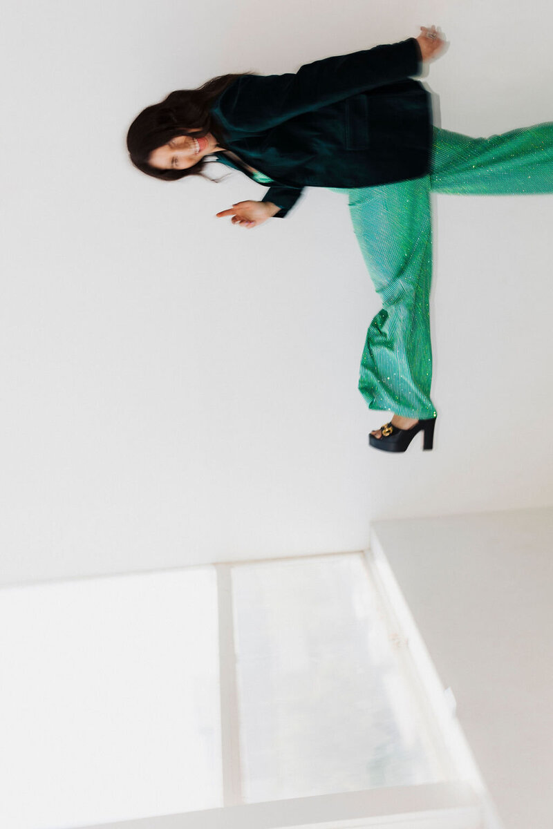 Samantha Piercy kicking up her leg wearing a green jumpsuit