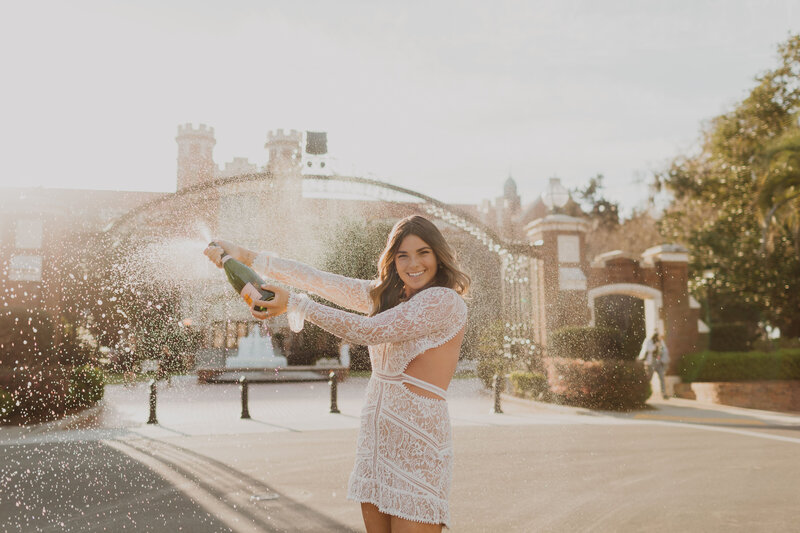 Senior girl popping champagne and smiling at the camera