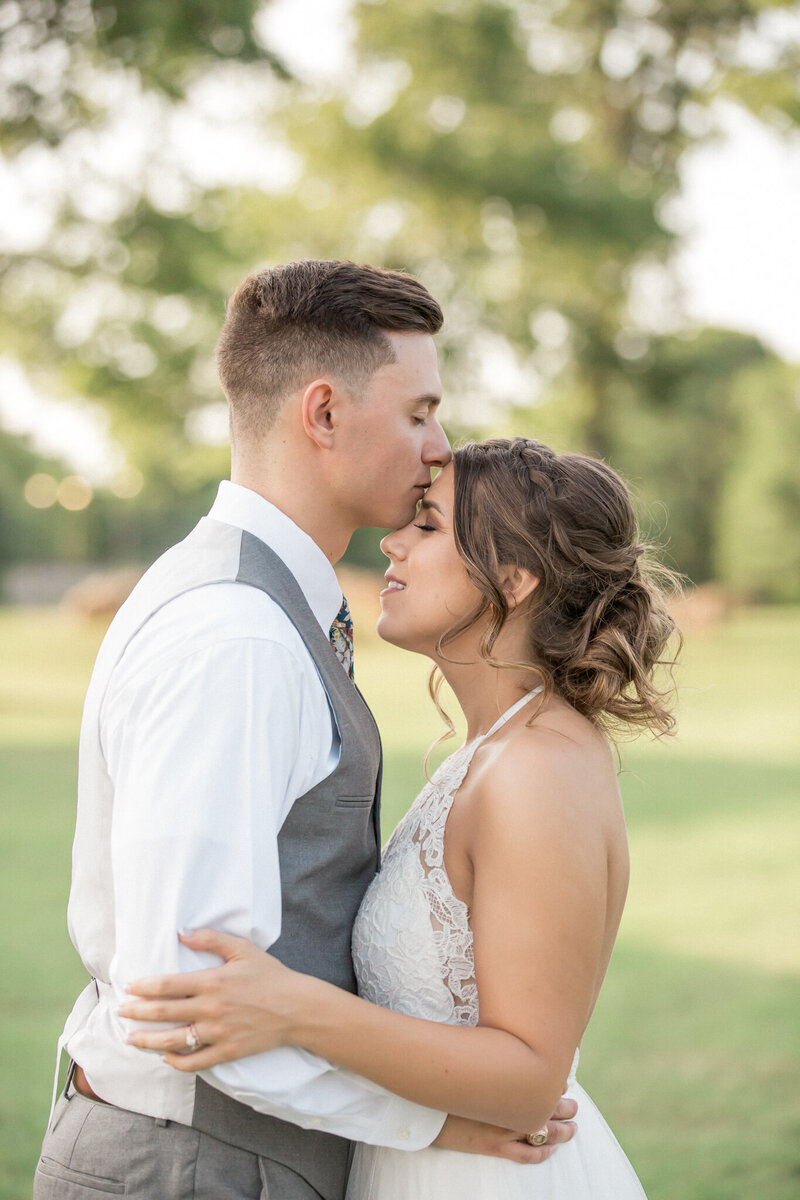a sweet moment as man kisses his new wife on the forehead outside of Boulder, Colorado