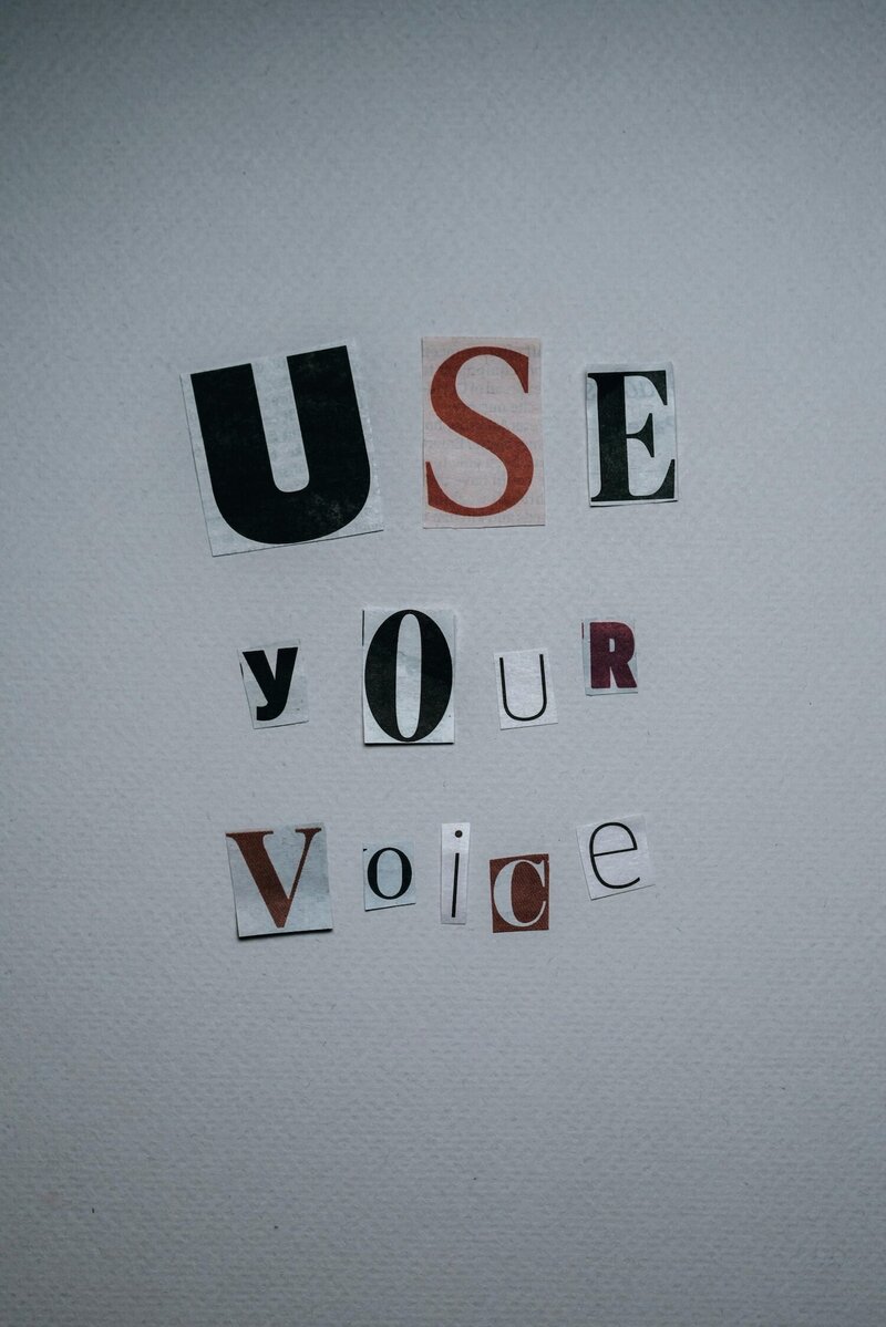 the words "use your voice" pasted as a collage on a piece of paper, representing the self-belief artists can find in community