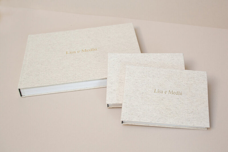Three linen wedding albums sit on a table.