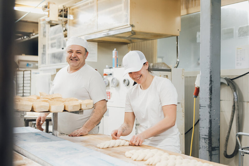 Bäcker Zeljko und Bäckerin Melanie formen gerade unseren Dinkelzopf und haben sichtlich Spaß bei der Arbeit