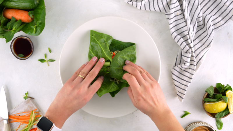 An image of a step in the recipe where Shahad is folding a lettuce wrap in with the ingredients showing