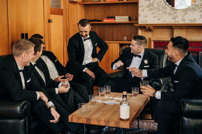 groom and groomsmen play cards in whiskey room at the winehouse in queenstown