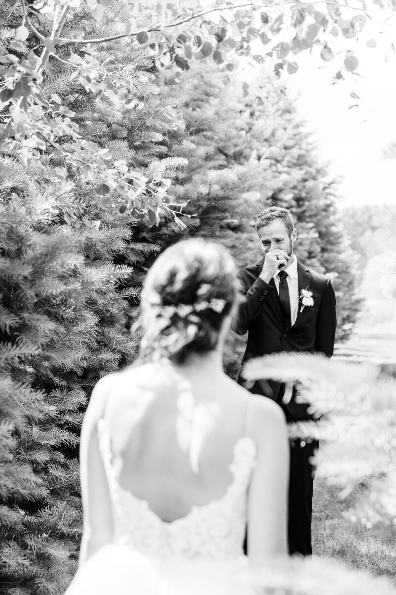 Bride walks up in anticipation to her groom with his back turned during their first look at their intimate Arrowwood farms wedding
