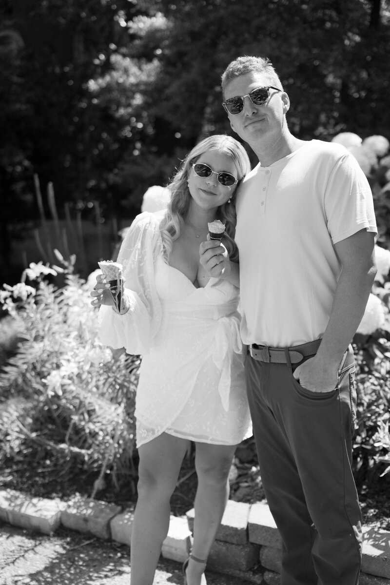 Couple share ice cream cones in sunlight wearing sunglasses