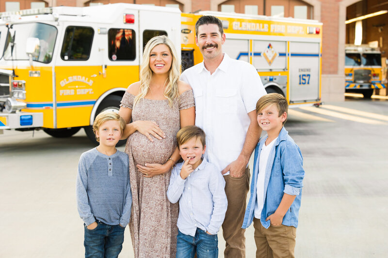 family smiling together with pregnant mom at fire station