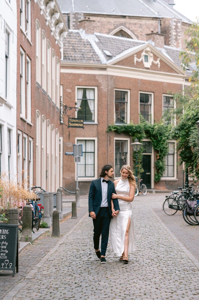 Een bruidskoppel wandelt gearmd door de stad Leiden