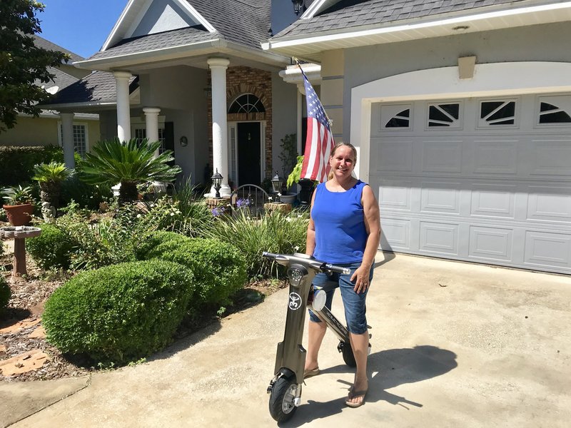 Lady sitting on her grey Go-Bike M1 with American flag in the background