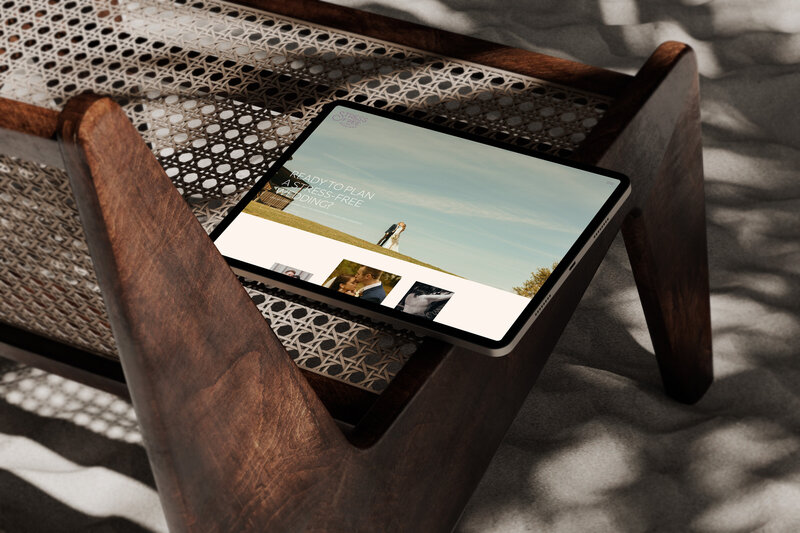 A tablet displaying a webpage is placed on a woven wooden bench with sunlight filtering through casting shadows, showcasing elegant showit template customization for wedding planners.