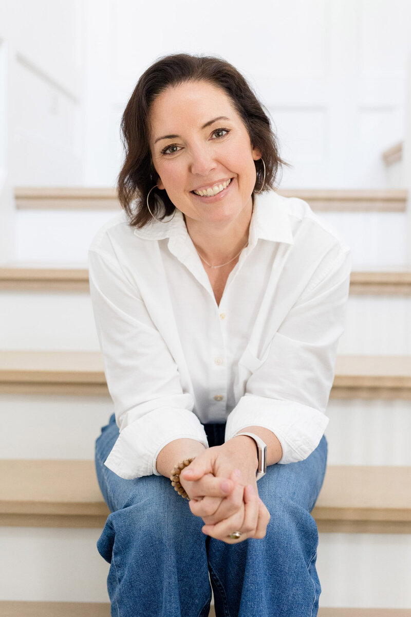 Life coach Dinah McBridge sitting on a staircase, smiling 