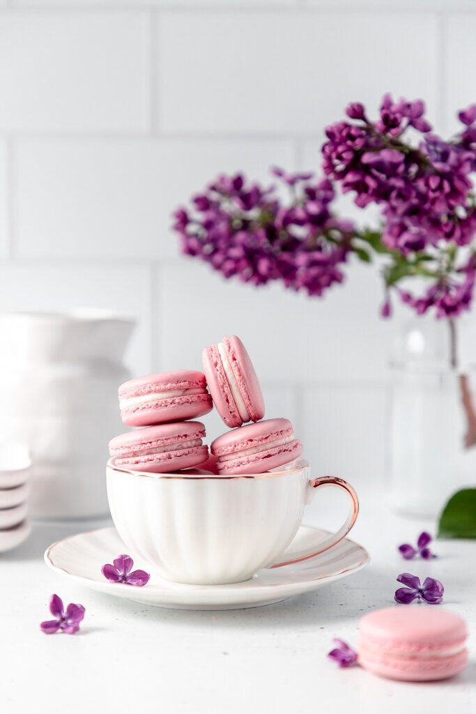 pink macaroons stacked inside of a tea cup