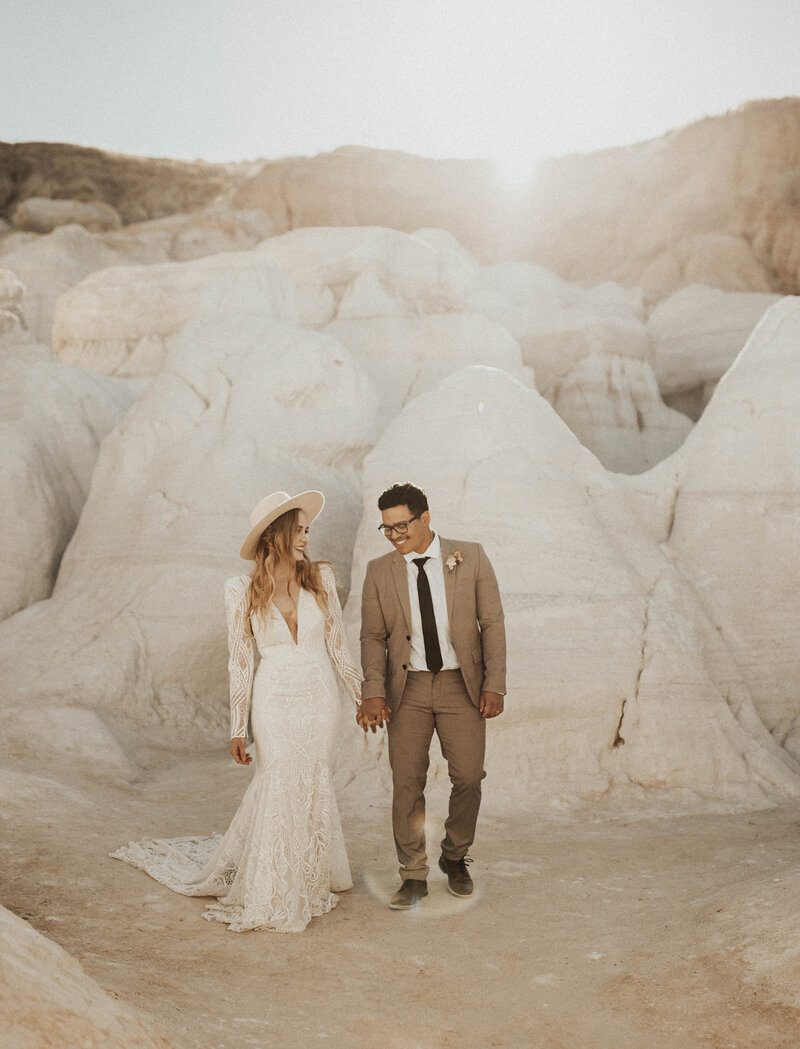 Bride and groom walking and laughing in canyon