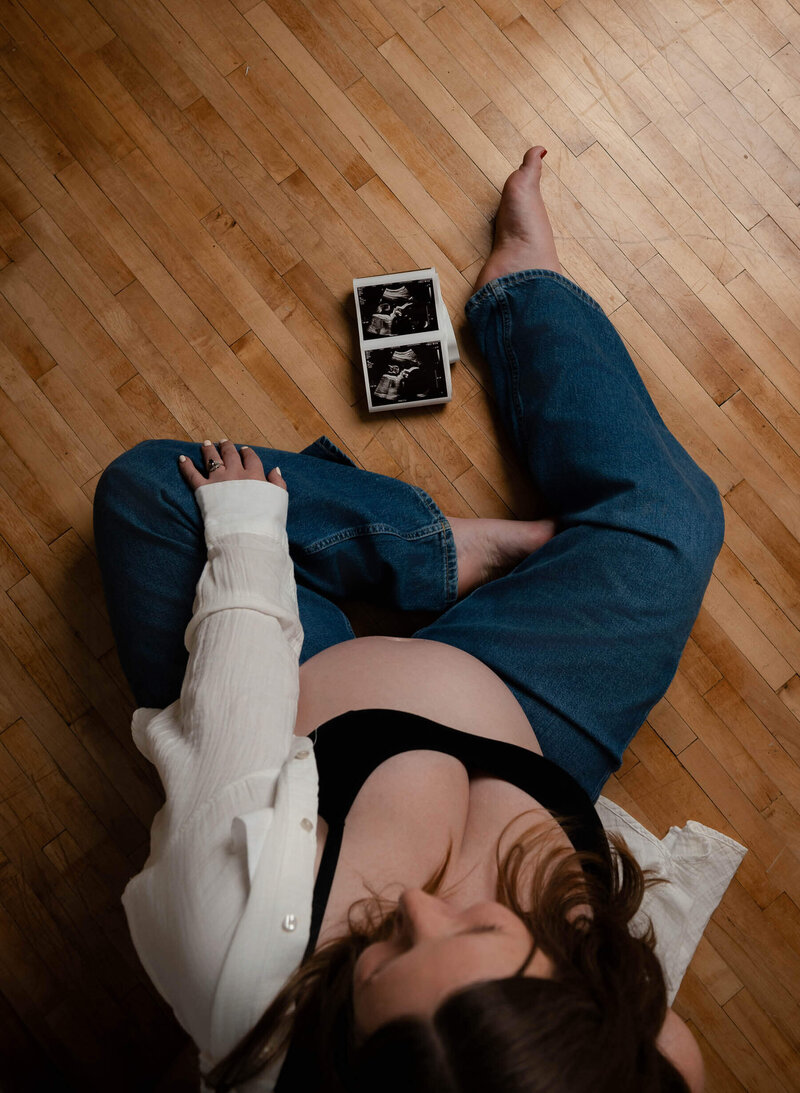 Pregnant woman on the floor with ultrasound image next to her