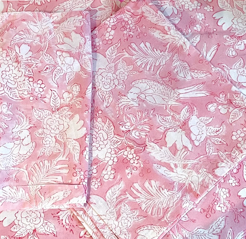 Pink paisley table linen featring pink background with whihte block prints of flora, fauna and birds