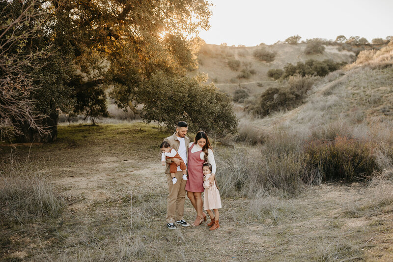 Family of 4 standing in front of a tree during golden hour