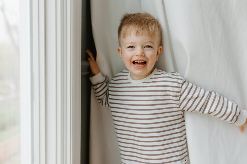 Blonder toddler boy laughing toward camera during family photos in St. Louis