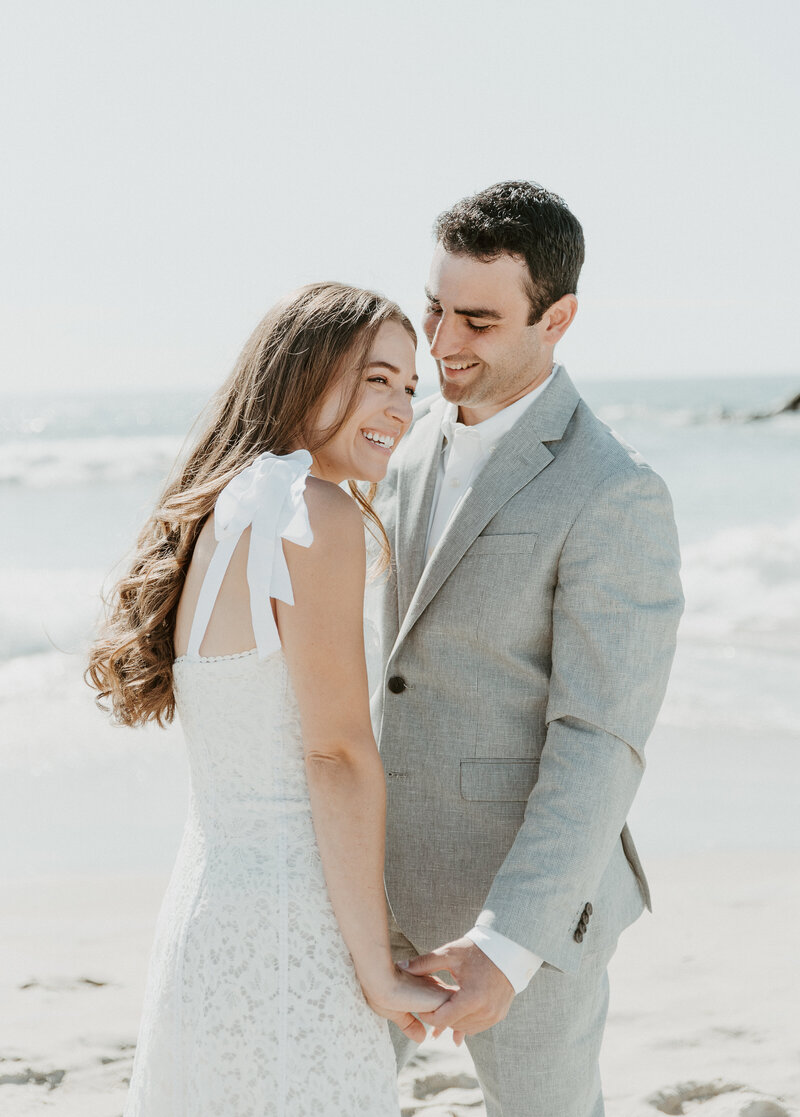 Bride and groom smiling on beach at California wedding