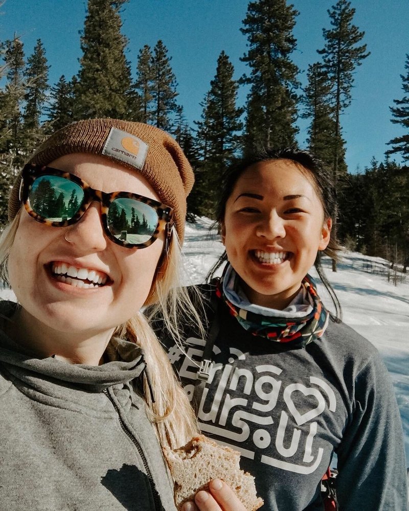 Emma Studley wearing sunglasses and smiling with friend outside in snow