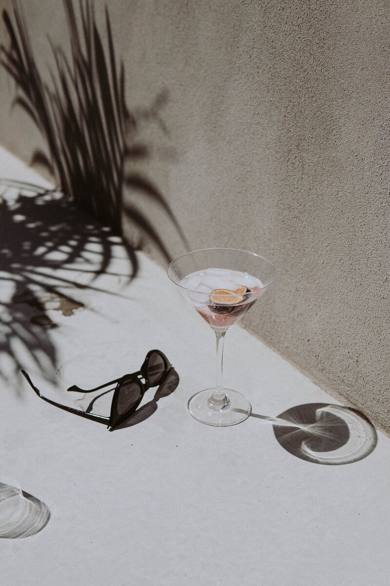 Sunglasses and martini on a sunny table