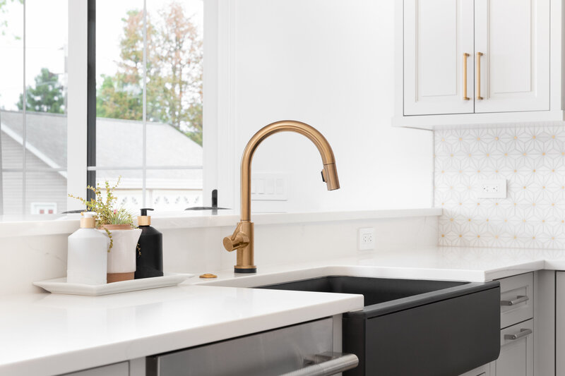 Brushed gold kitchen faucet with  farm sink and white countertop in this newly remodeled kitchen. 