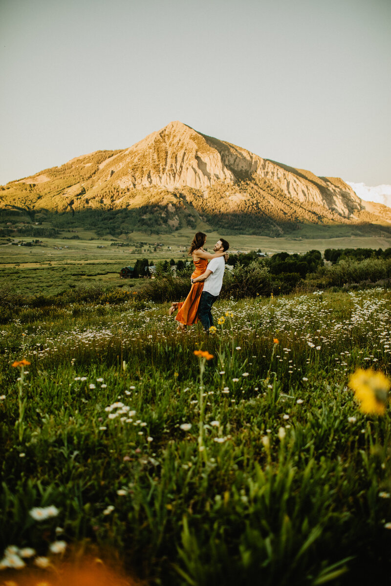 man holding woman in a field while they kiss