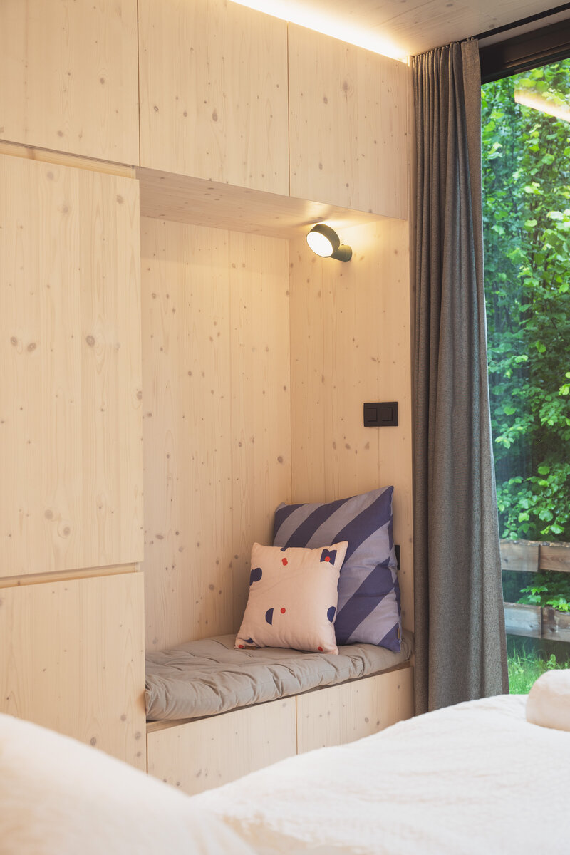 Cozy reading nook inside a wooden Tiny Home cabin at The Campus Alps.com, offering a peaceful retreat surrounded by nature, perfect for relaxation during private getaways or company retreats.