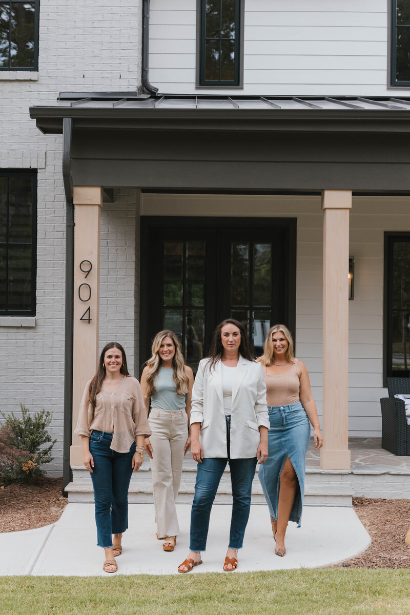 Raleigh Real Estate Agent, Jacie Dykes, wearing black dress sitting in modern living room in Raleigh New Construction home.