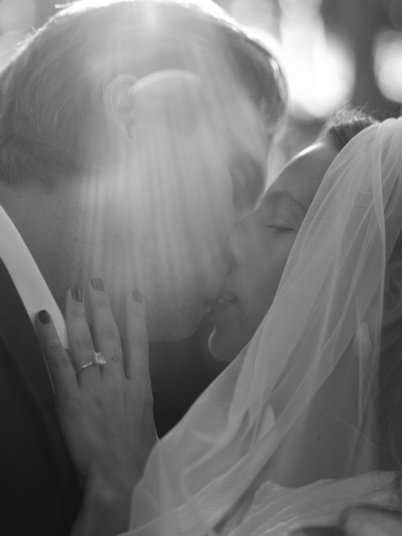Couple kissing with sun beams on them at California wedding