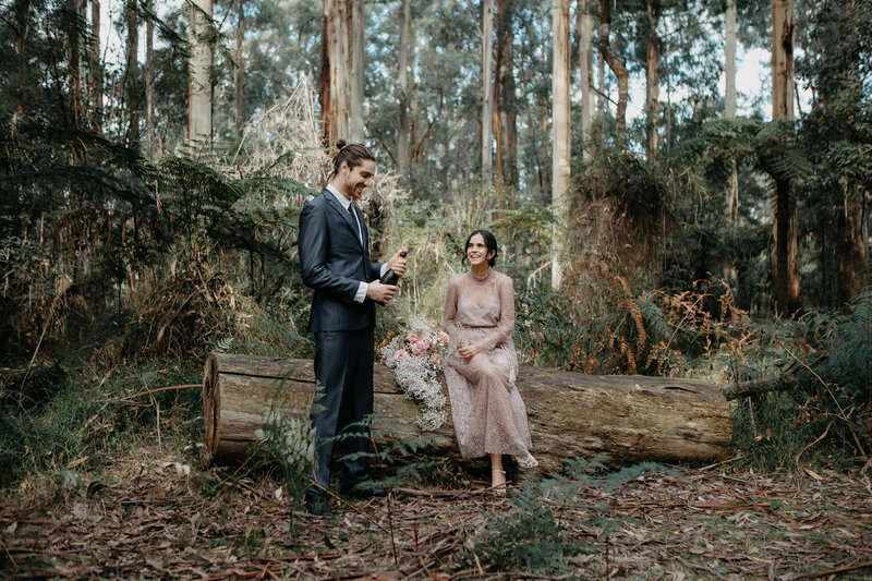 bride and groom popping champagne in the forest