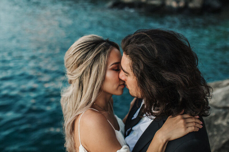 bride and groom embracing on oceans edge