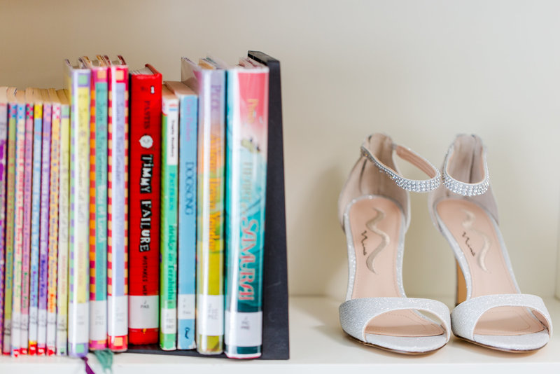 Wedding shoes on a Library bookshelf with a stack of books