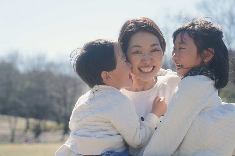 公園でママと子どもたちが楽しくじゃれ合う自然な写真