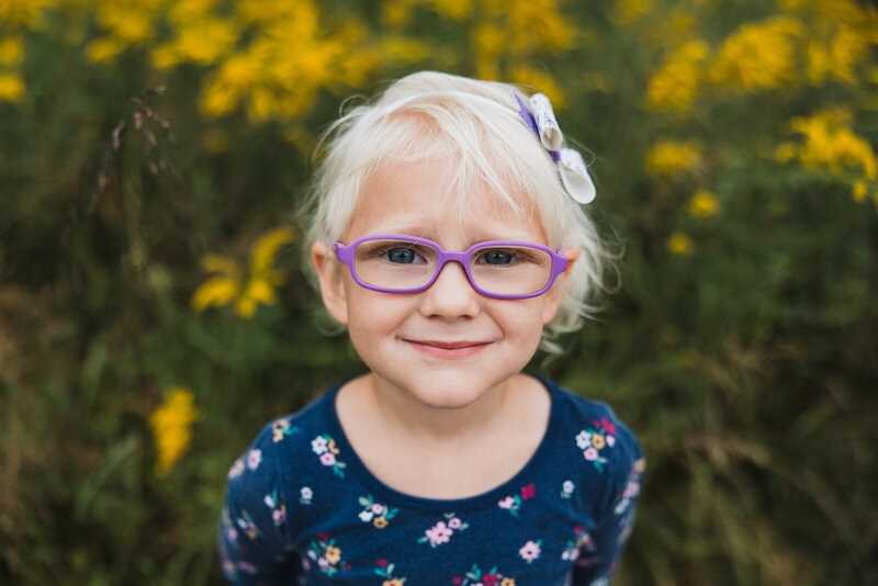 Close-up portrait of a girl wearing purple glasses during a family photo session in Farmington, Missouri.
