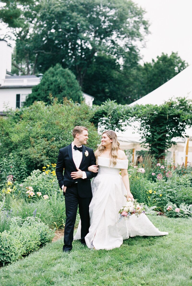 bride raises bouquet in excitement as she walks down aisle with her husband at Newport Wedding