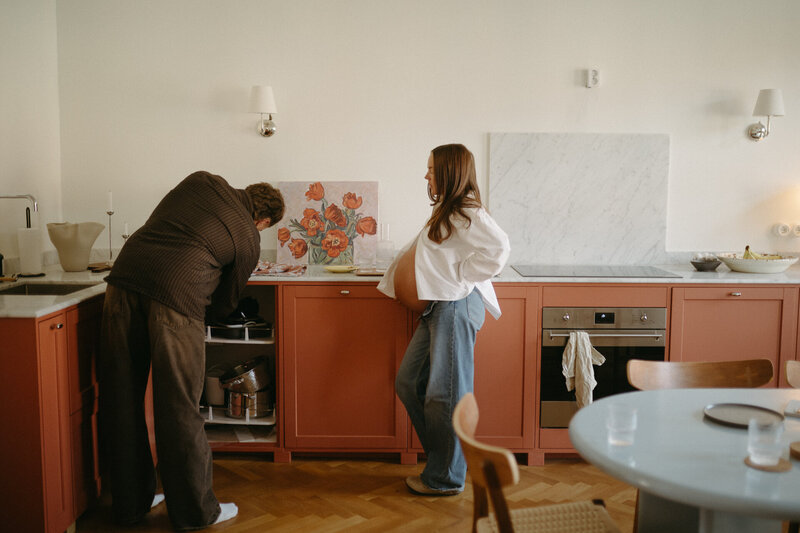 Ett par som väntar barn grejar i köket. Gravidfotografering Göteborg.  