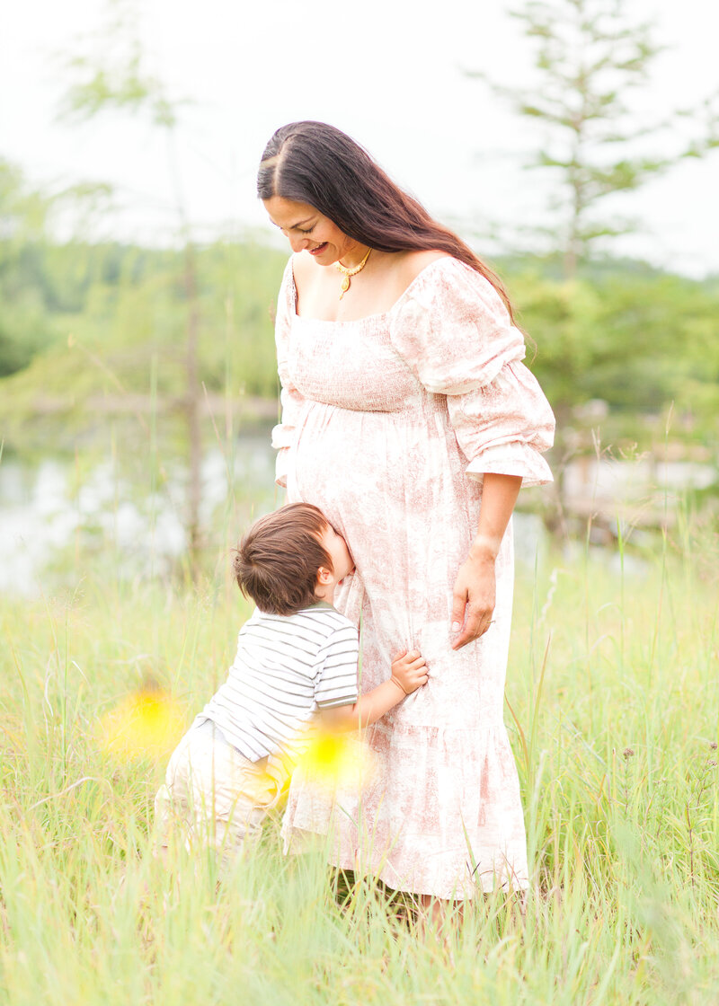 Toddler kissing Mom's belly while awaiting baby's arrival, candid motherhood photography by Heirloom Story Co.