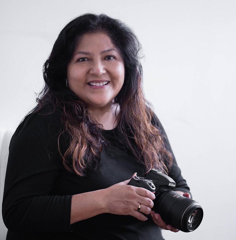 picture of Patricia Parrales with camer looking at photographer's camera.