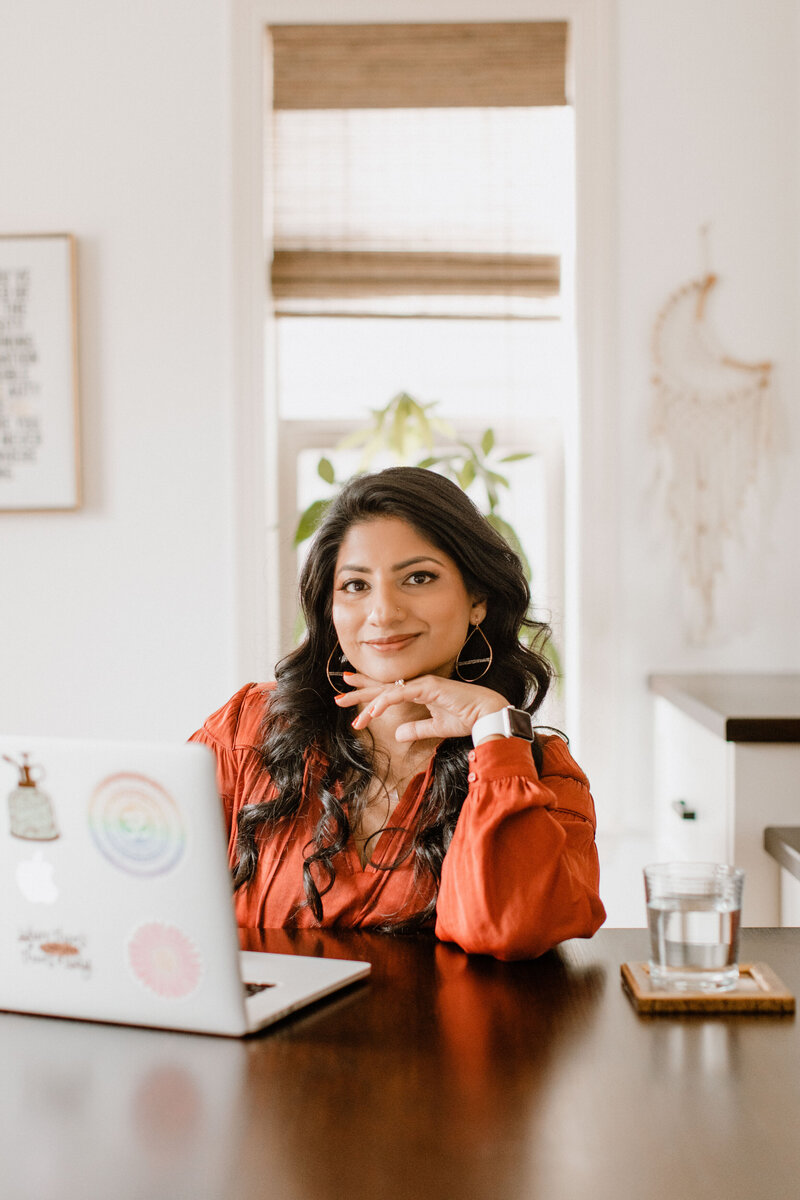 Mindfulness coach Radhika sitting at a table looking at a laptop