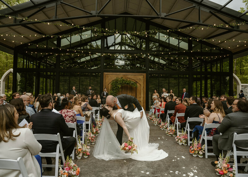 groom dips bride and kisses her while walking back down the aisle after just saying I Do in richmond, va