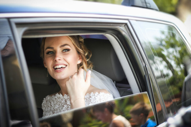 Smiling bride looking out the window of a car on wedding day