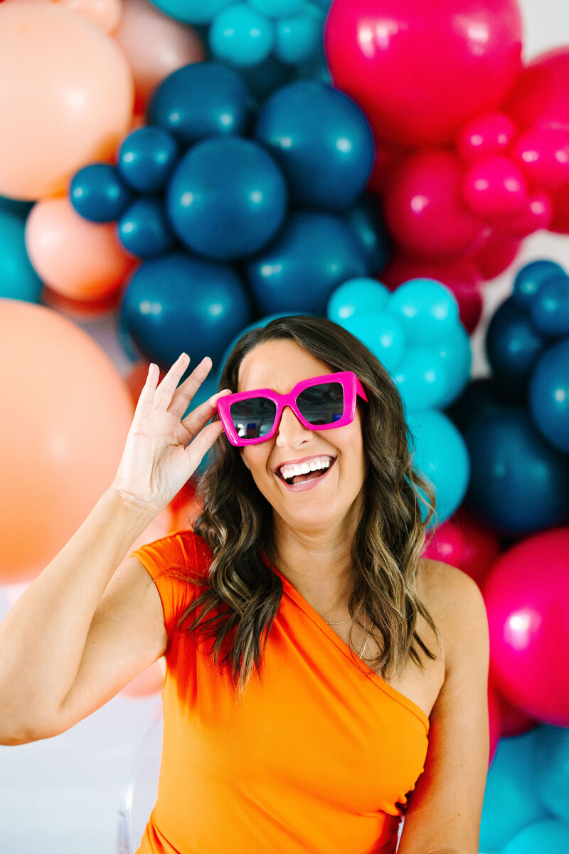 Raleigh Balloons, Event Decor and Rentals expert in a pink fun dress with Pantone accents presenting the balloon sizing guide and creative décor services