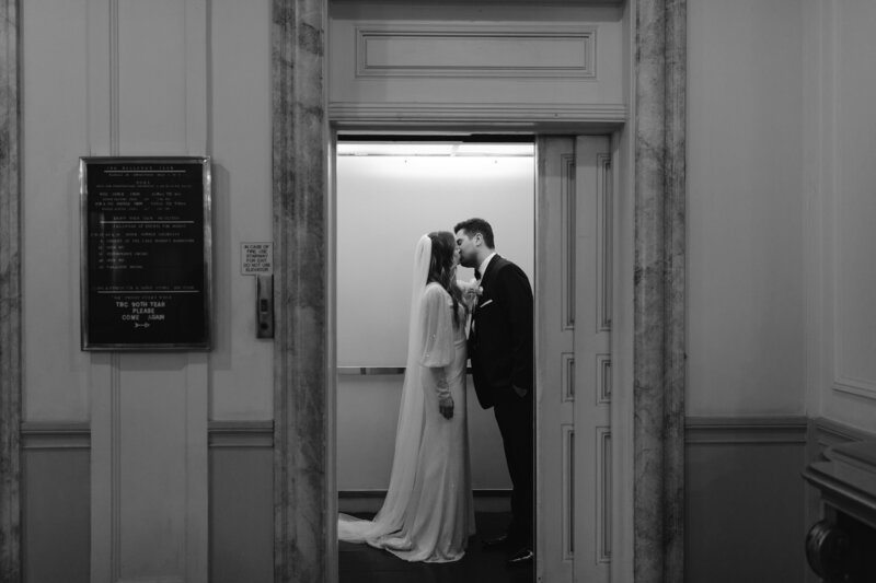 Newly weds kissing in elevator of vintage hotel as the door closes