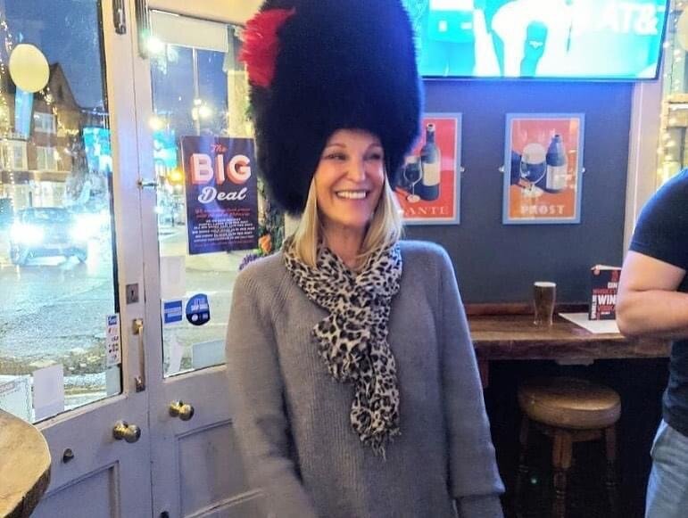 Woman tries on British Coldstream Guards black fur hat in Windsor, UK pub