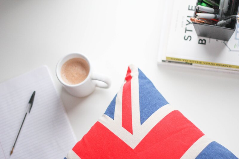Notebook, cup of tea and cushion next to the British flag