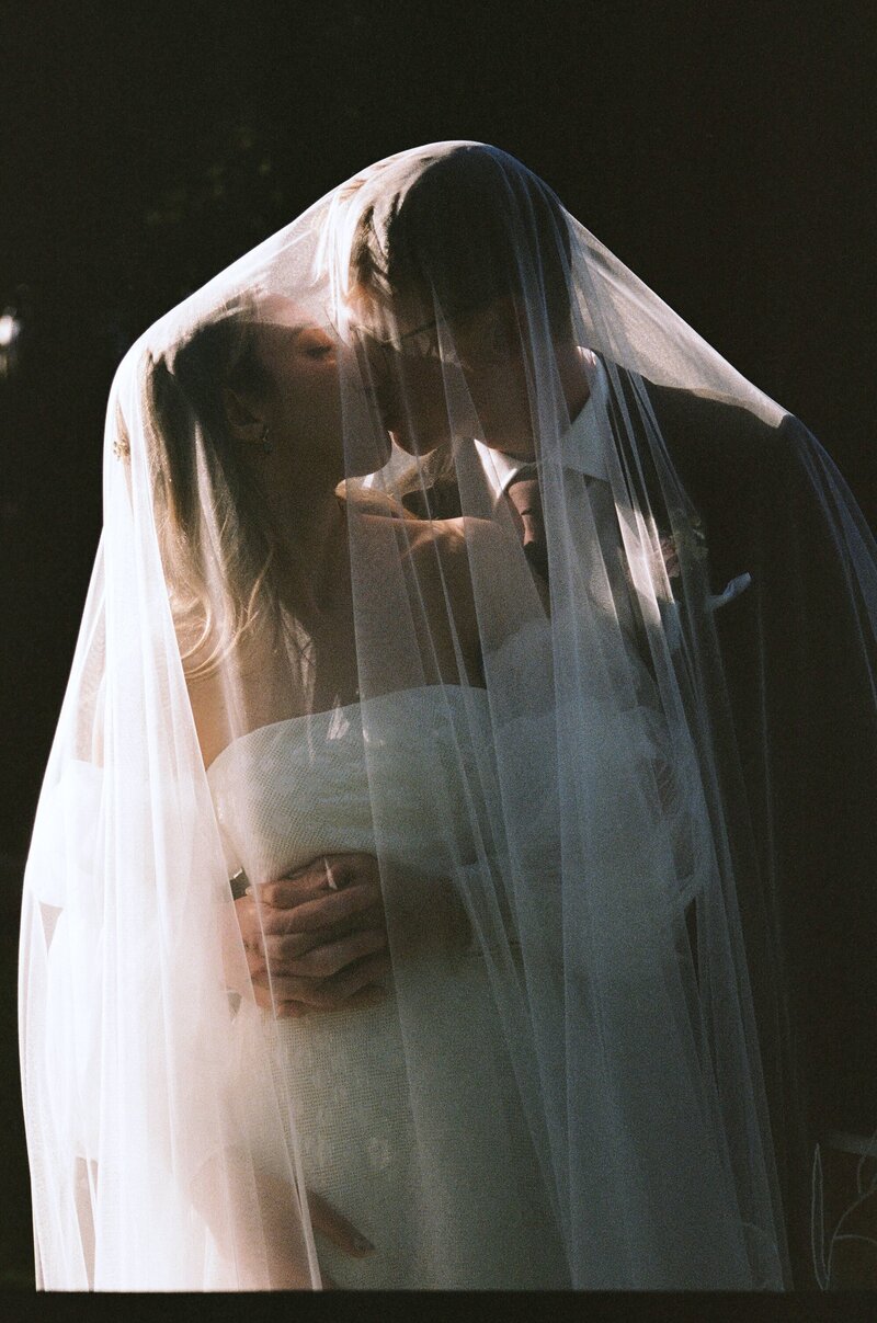 A bride and groom share a kiss under her veil