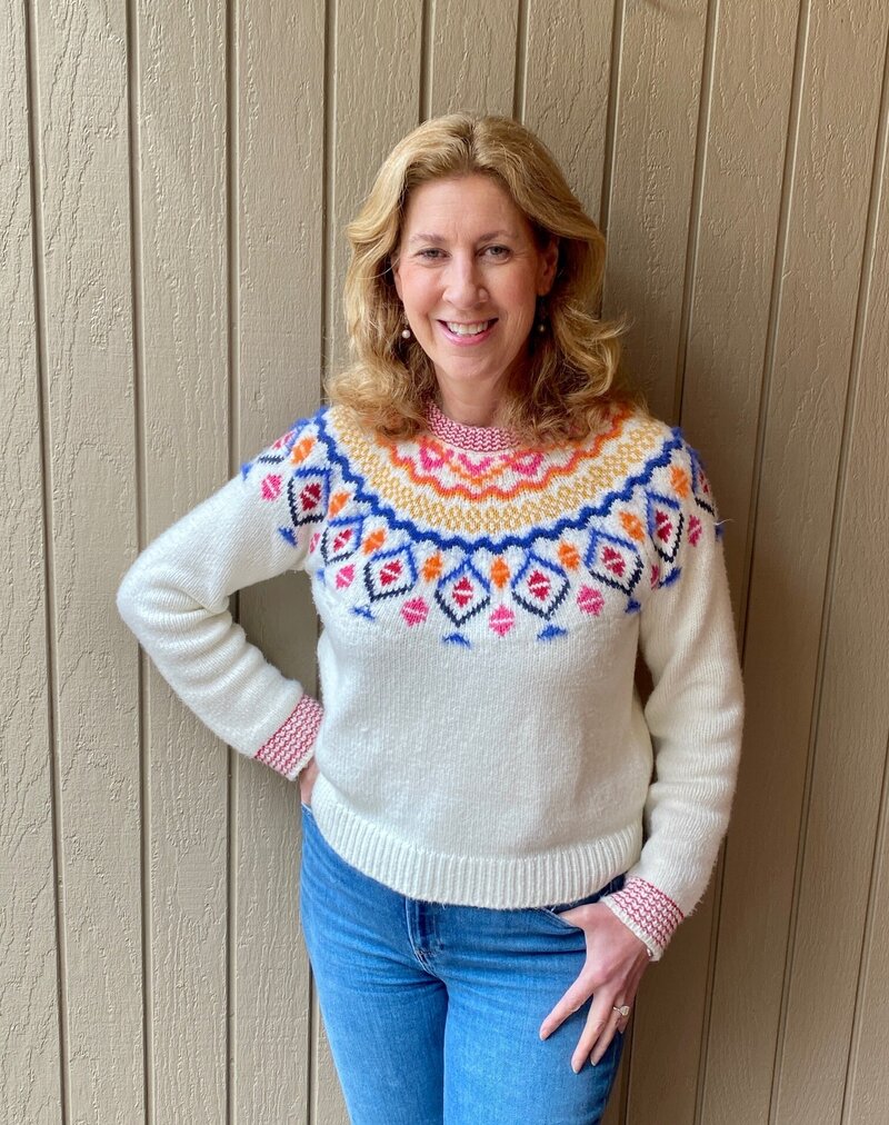 Francesca Lohman smiling and standing against a tan paneled wall, representing the owner of an East Bay home improvement company.