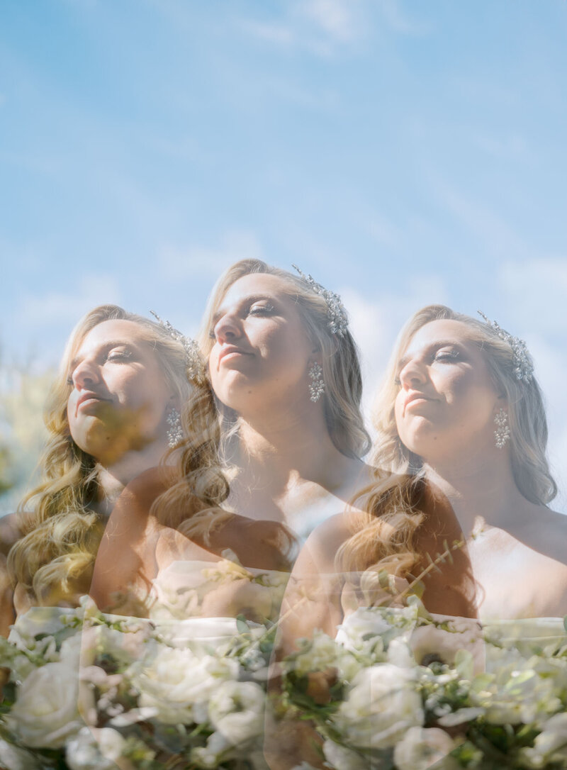 Dreamy triple-exposure portrait of a bride under a blue sky