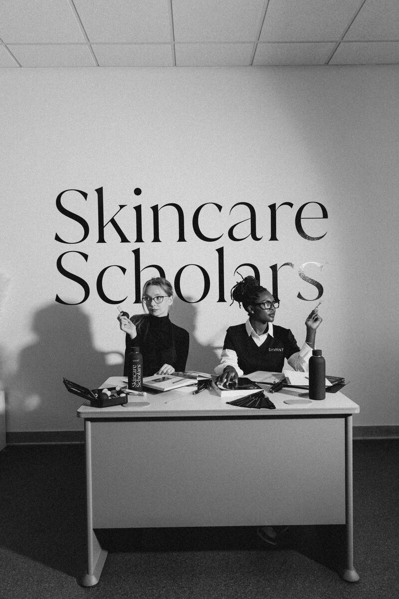 A close-up of an aesthetics student taking notes on skincare treatments during a class at Savant Aesthetics Institute, with textbooks and notebooks on the desk.