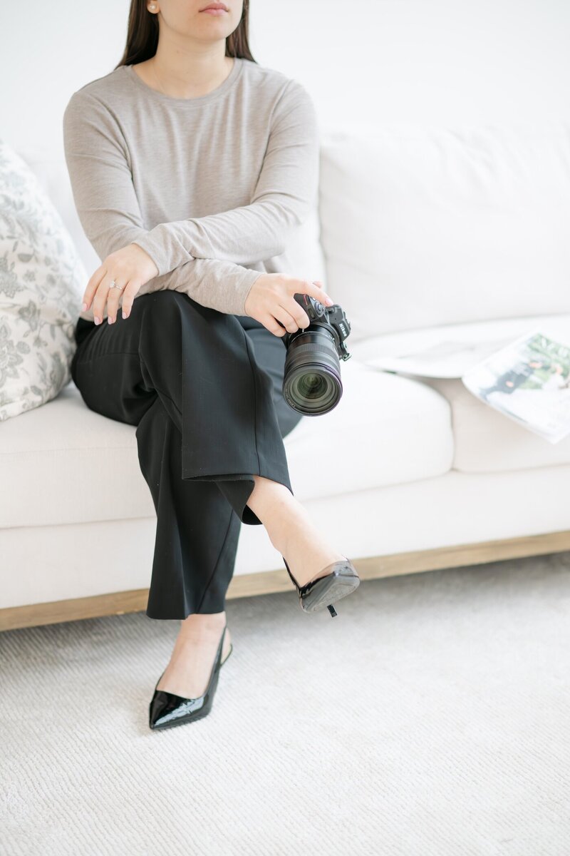 Ephe crosses her legs, holding her camera near her shins.